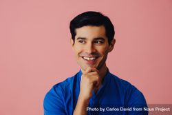 Latino man smiling in pink studio with hand on chin 41gAl0
