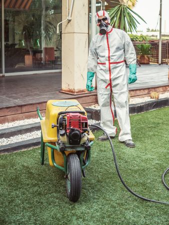 Specialist in uniform for fumigation holding yellow trolley in yard