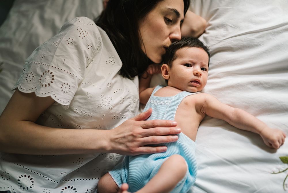 Mother and baby lying on bed