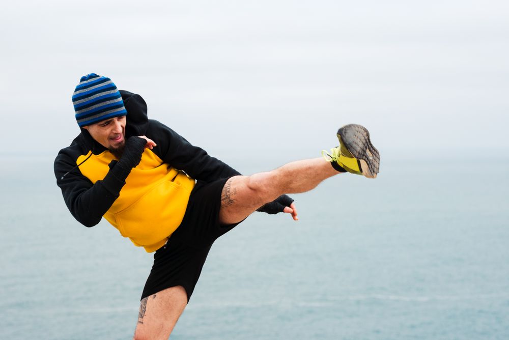 Kickboxer training on cliff near sea