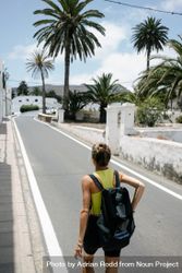 Back of sporty woman walking on quiet trees surrounded by palm trees 5XzYkb