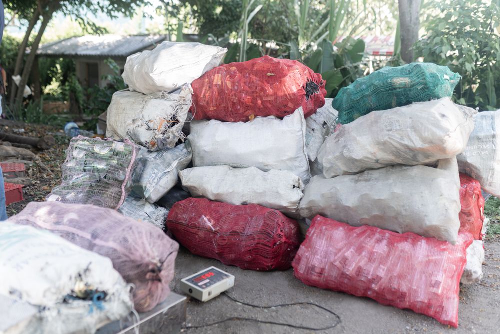 Recycled Glass Bottles in Sacks Being Weighed on Large Scale