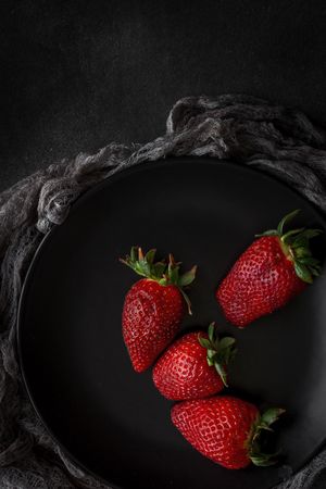 Red and fresh strawberries flat lay in dark dish