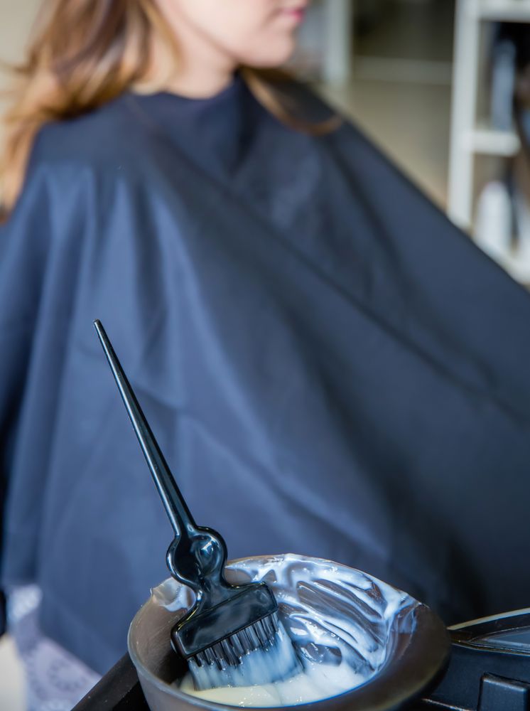 Close up of hair dye formula with client in chair behind