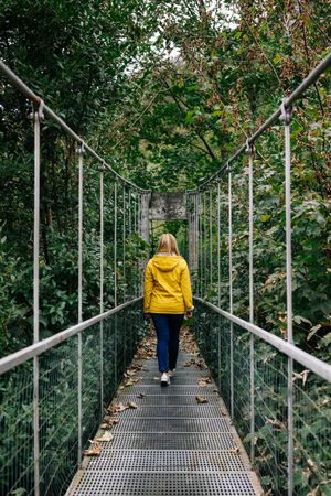 Cheerful female tourist standing on hanging bridge in summer
