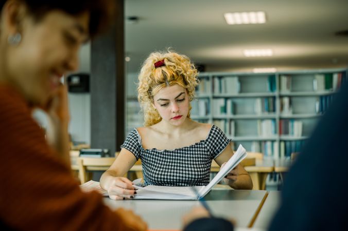 Focused woman reading book in library