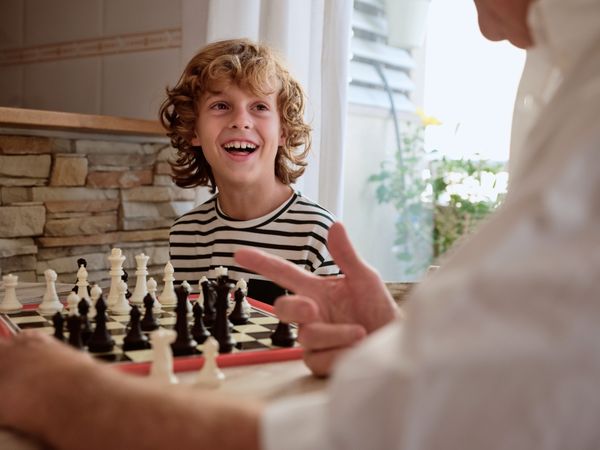 Faceless grandparent playing chess with boy