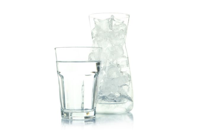 Glass carafe full of ice with glass of water