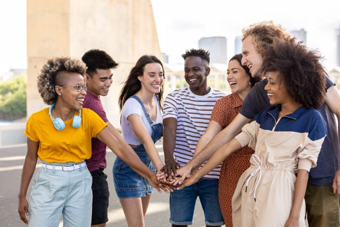 Group of young adult friends with hands on stack showing international unity