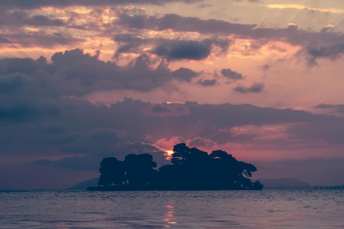 Sun setting behind a small island in the ocean