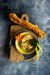 Traditional hummus spread with breadsticks and crackers to dip