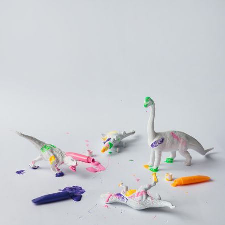 Plastic dinosaur splattered with different colors of paint