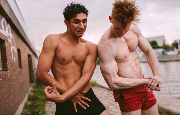 Two male friends playfully showing their muscles