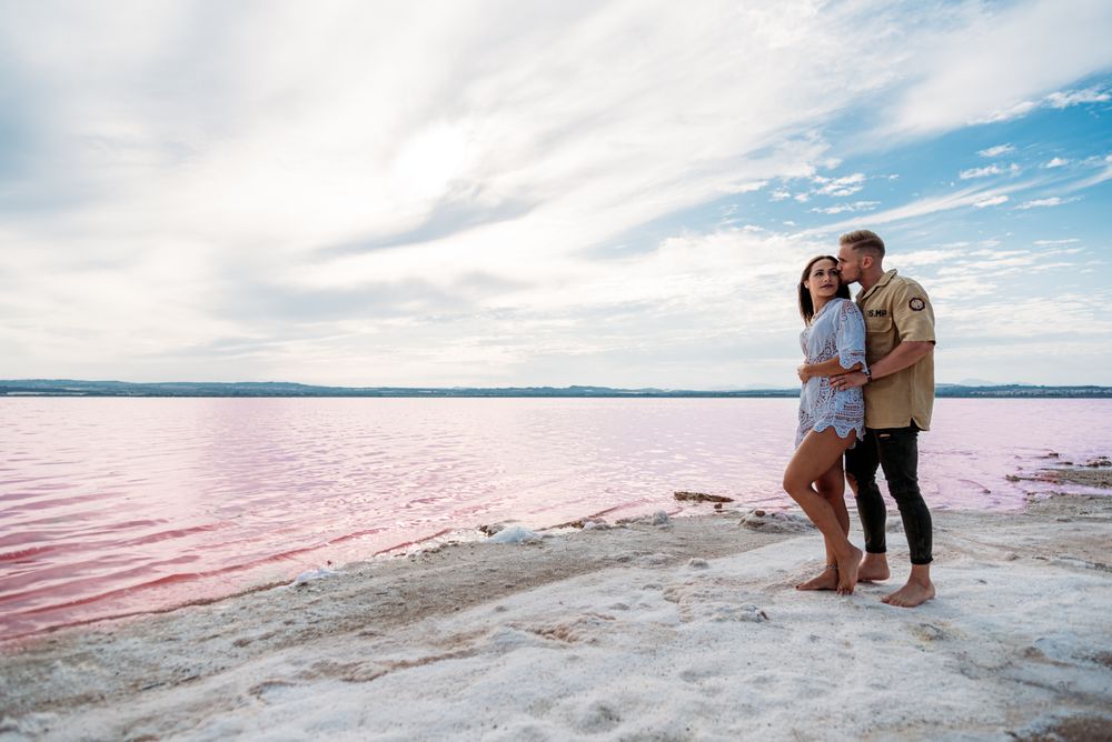 adorable couple standing on an amazing beach with pink water