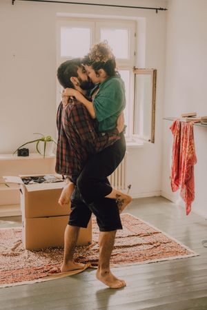 Happy couple embracing in room next to cardboard boxes