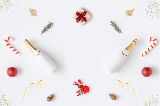 Holiday decorations; Champagne, candy cane and present, arranged symmetrically on light background