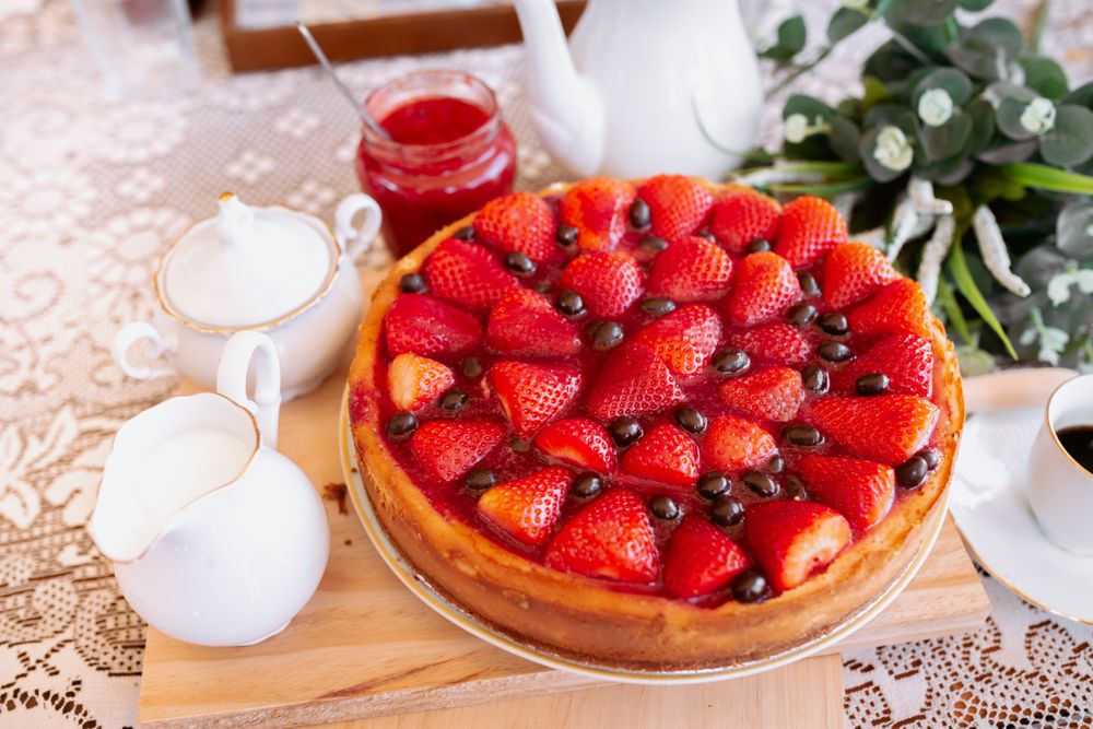 from above a strawberries cake on table with coffee and milk