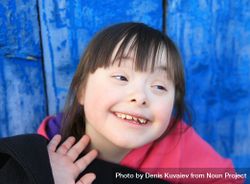 A girl with an intellectual disability smiling against a bright background 5RpvDb