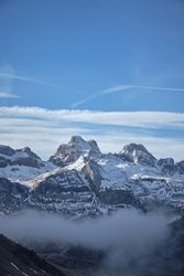 Snowy mountains and mist against blue sky
