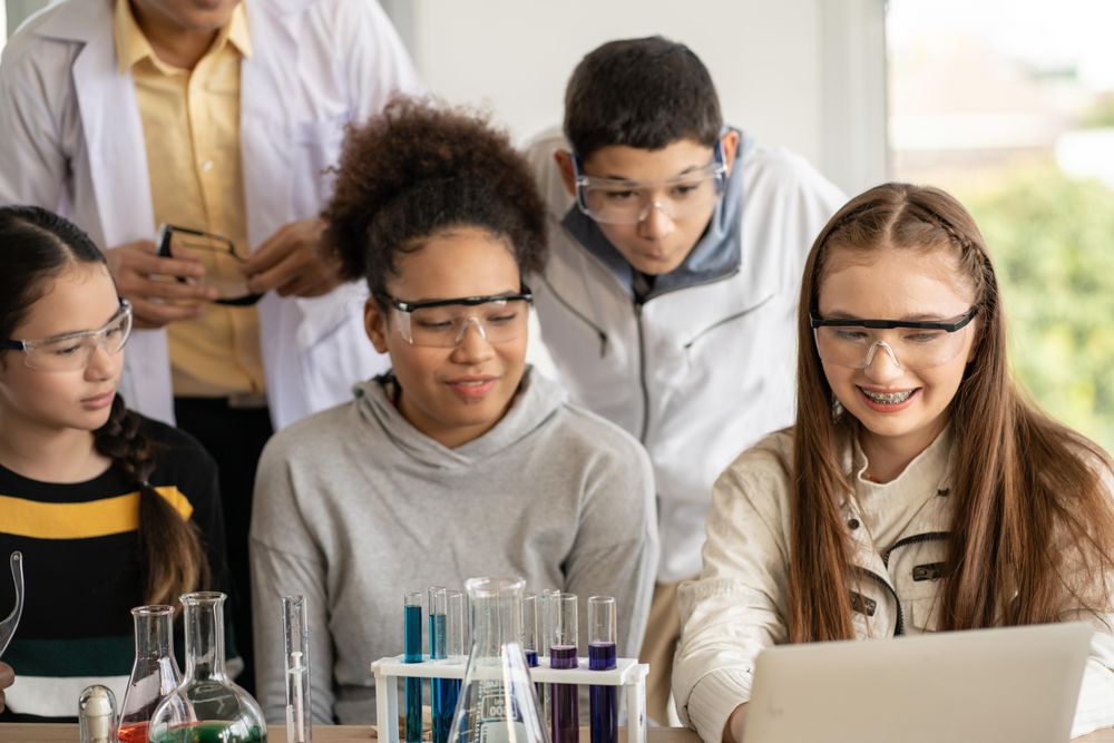 Smiling multi-ethnic students in protective eye wear with teacher