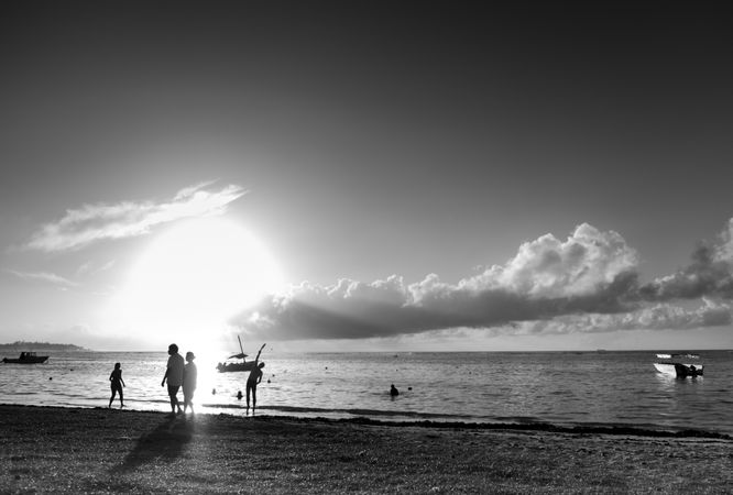 Silhouettes of people on tropical beach, monochrome
