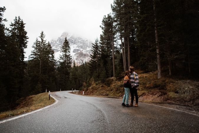 Casual resting couple standing in an embrace on route amid forest