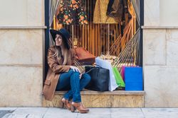 Content young woman in casual outfit resting on street after shopping