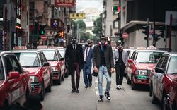 Men is suit wearing gas masks walking on street during Hong Kong protest