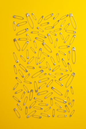 Scattered safety pins on yellow background