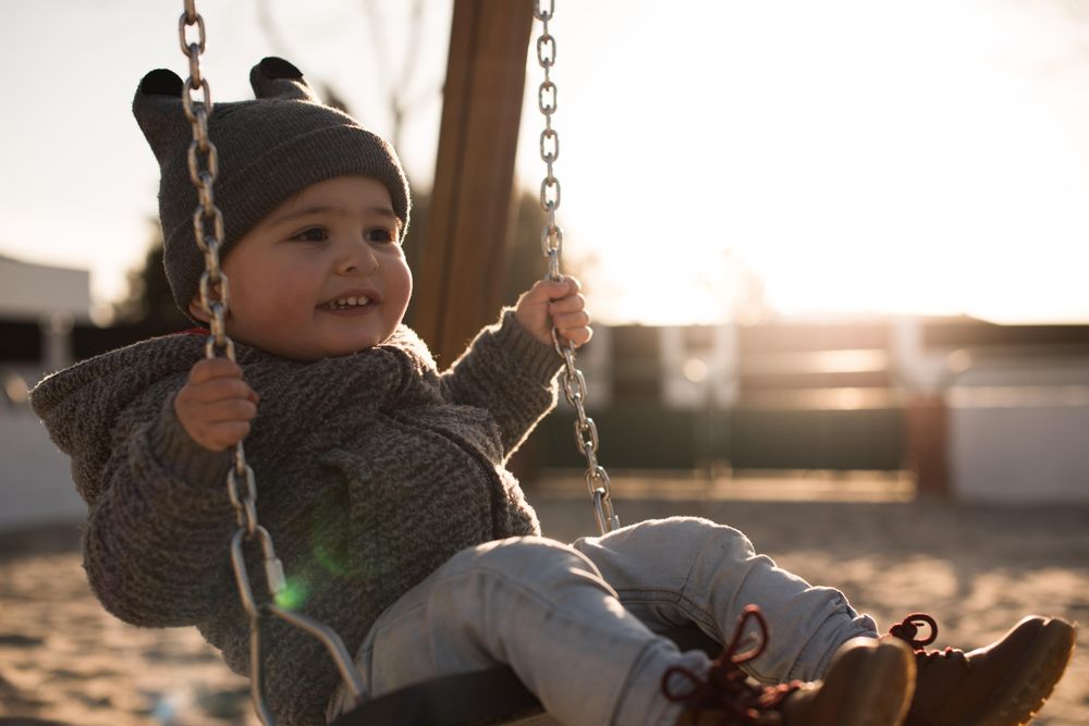 Boy in gray jacket sitting on swing