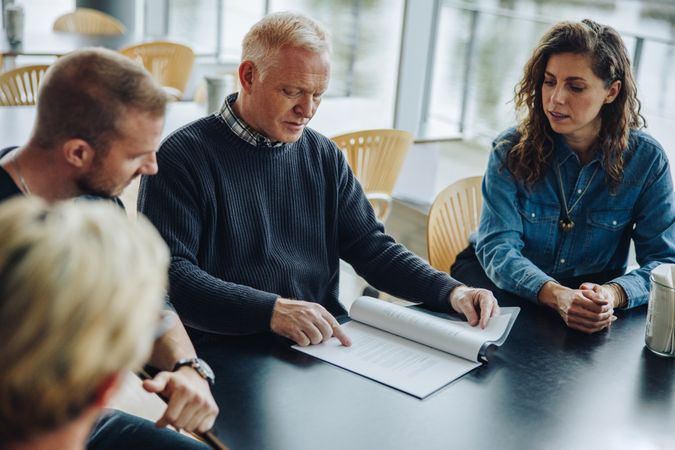 Older professional man explaining document to colleagues