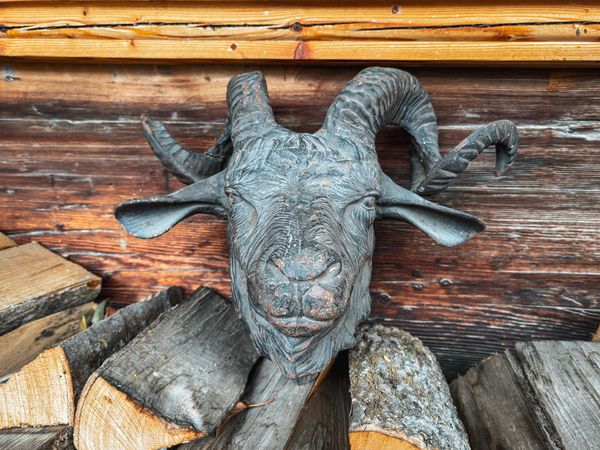 Mountain goat figurehead on pile of logs in Rossiniere, VD