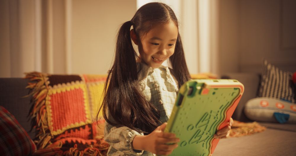Portrait of Smart Little Girl Using Digital Tablet Computer at Home.