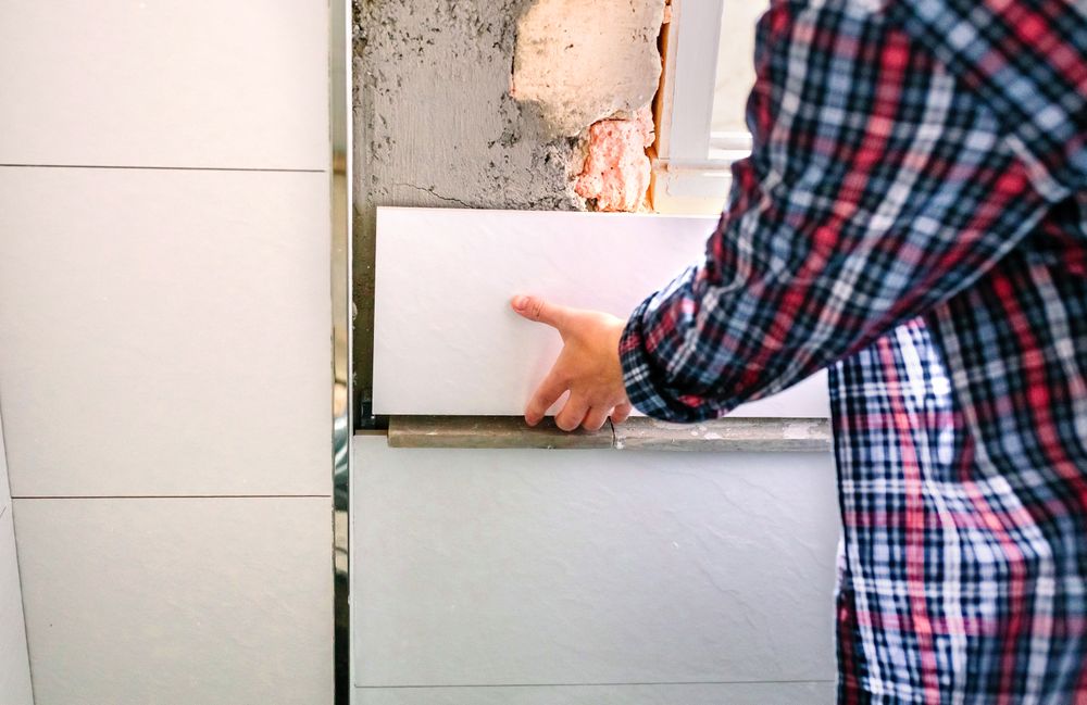 Unrecognizable female bricklayer laying tile on the wall