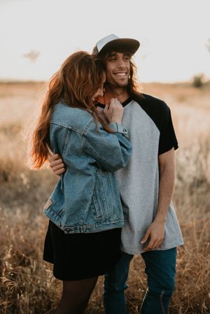 Hipster couple bonding on field in sunlight