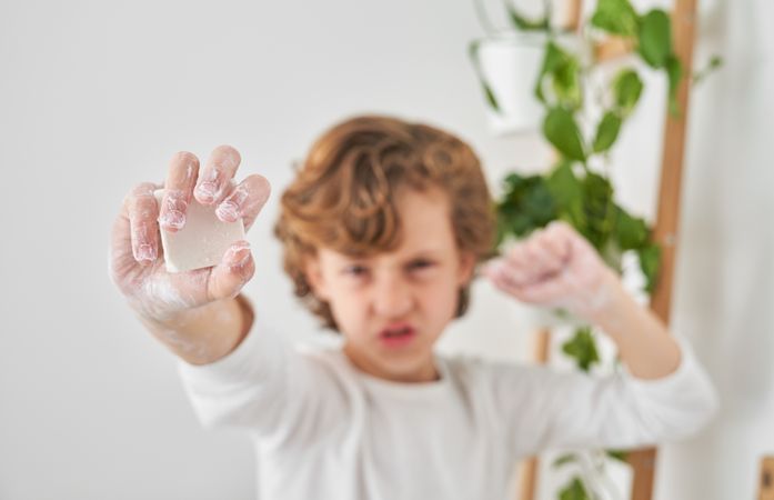 Funny boy outstretching arm with soap and clenching fist