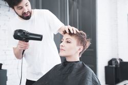 Hairdresser drying hair to woman