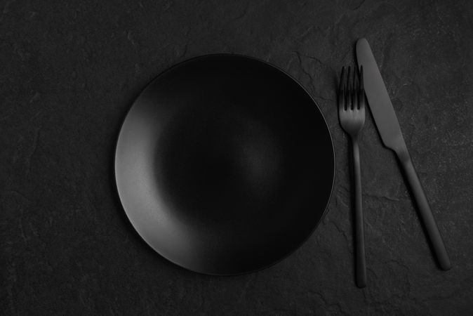 Dark matte plate, fork and knife on dark table