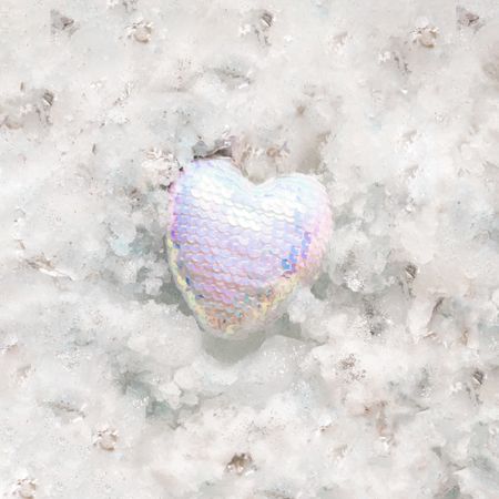 Heart in iridescent sequins on snowy background