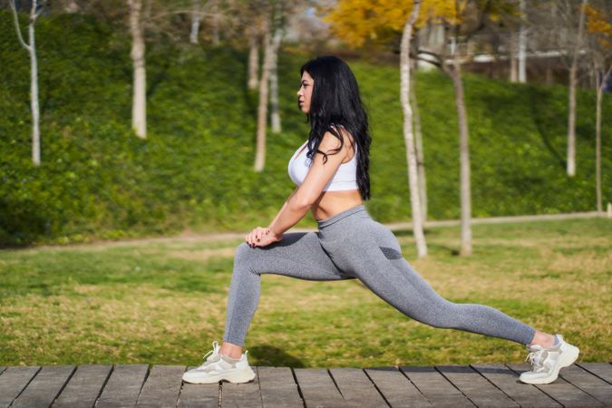 Smiling black woman stretching legs in park