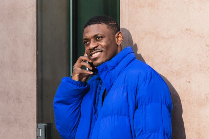 Cheerful stylish Black man chatting on social media on cellphone