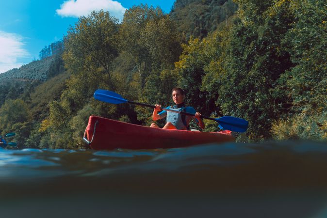 Young female kayaking on nature background