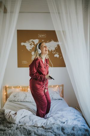 Woman with headphones dancing in bed