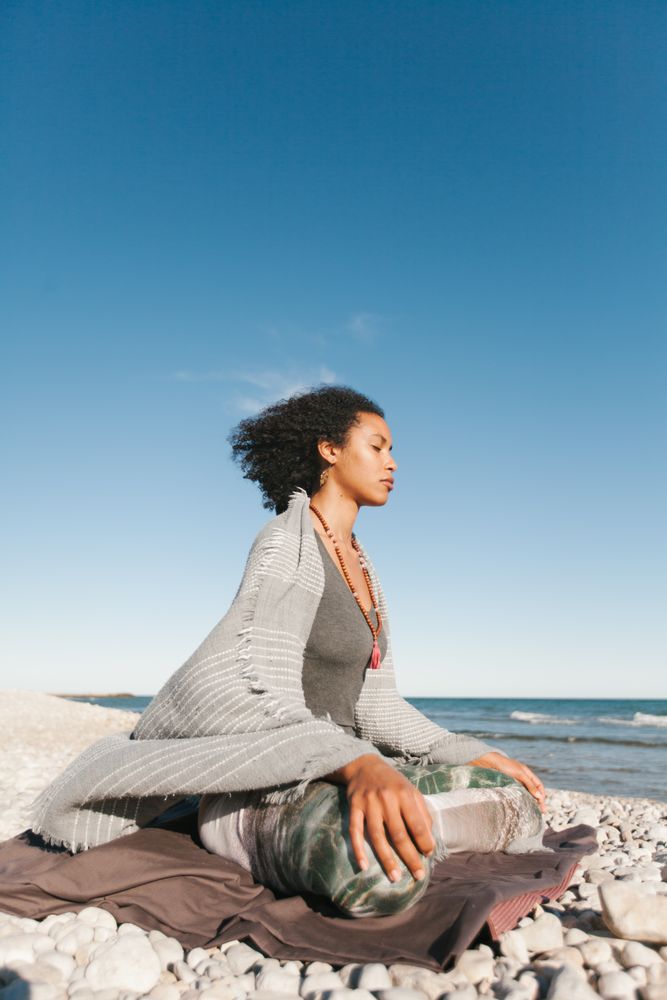 Sportive woman sitting on sandy beach in asana