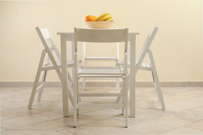 table with fruits and folding chairs in kitchen room