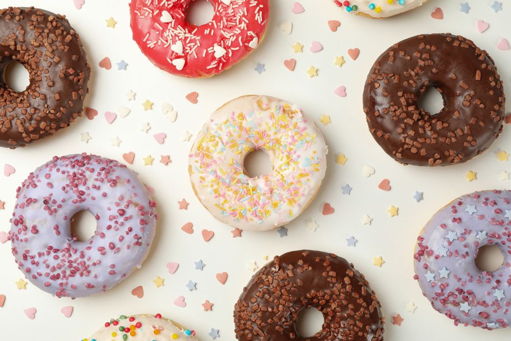 Flat lay with tasty donuts on plain background