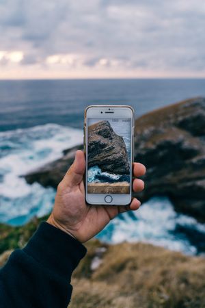 Person taking photo of cliffs and sea