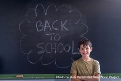 Boy standing at board with "back to school" written in chalk 0VBRD0