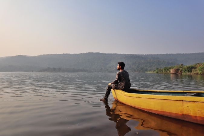 Man sitting on yellow kayak on body of water