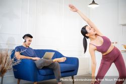 Woman stretching with partner on sofa in the background 4BDVd0